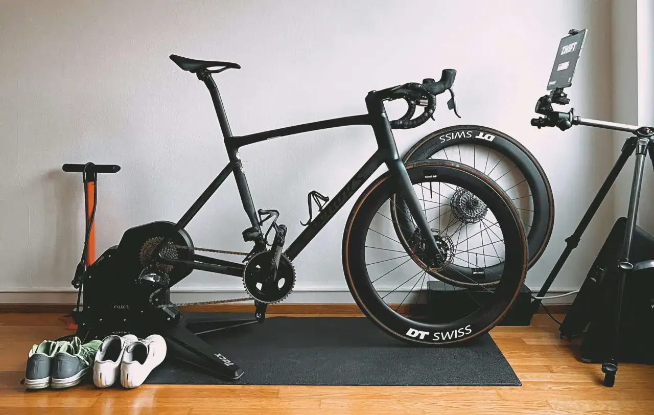 Rower szosowy na trenażerze Tacx Flux S, gotowy do treningu FTP. Obok buty kolarskie i pompka.