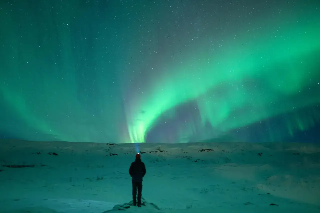 Widok na zorzę polarną nad ośnieżonym krajobrazem. Czy na Antarktydzie jest zorza polarna? Tak, można ją podziwiać!