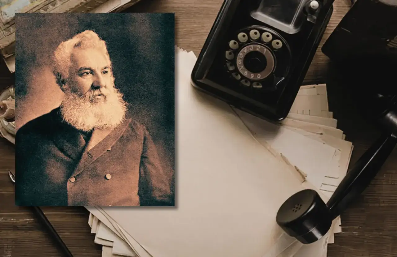Portret Alexandra Grahama Bella, kiedy wynalazł telefon. Obok leży zabytkowy aparat telefoniczny i stos papierów.
