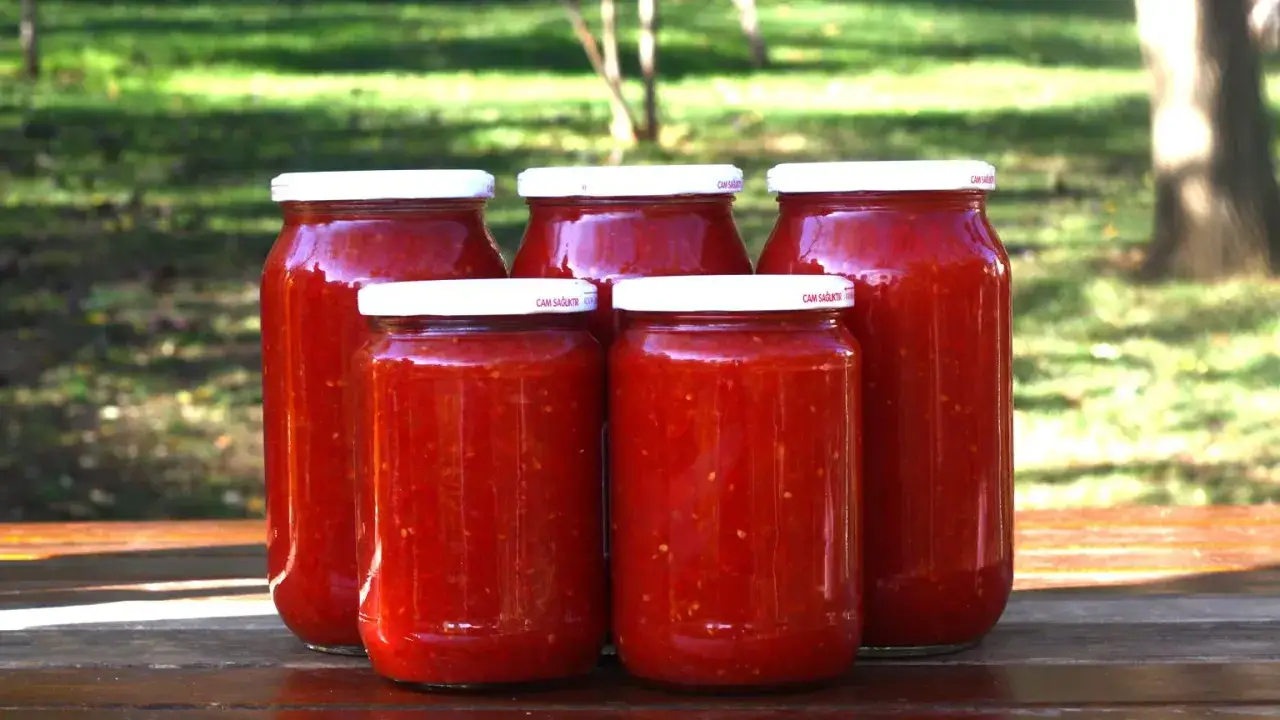 Pięć słoik&oacute;w z przetartymi pomidorami, gotowych na zimę. Domowe przetwory z pomidor&oacute;w to smak lata przez cały rok.