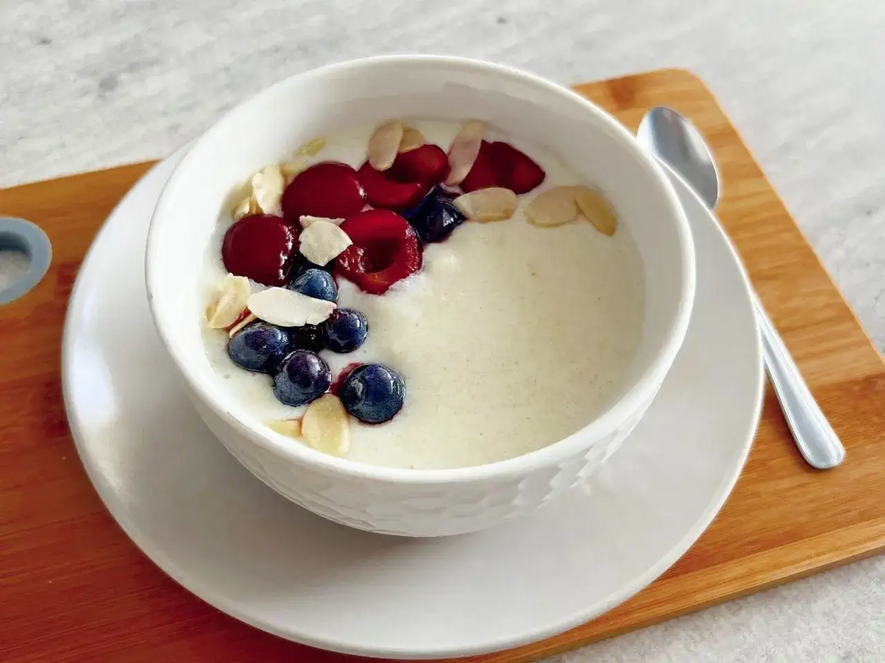 Pyszna kasza manna na mleku z jagodami, wiśniami i płatkami migdałów. Idealna proporcja, ile wsypać kaszy manny na litr mleka, by uzyskać taką konsystencję.