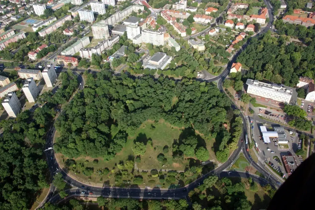 Widok z lotu ptaka na miasto z parkiem pośrodku. W oddali widać bloki mieszkalne i budynki. Trudno ocenić, ile jest rond w Polsce, ale ten widok pokazuje jedno z nich.