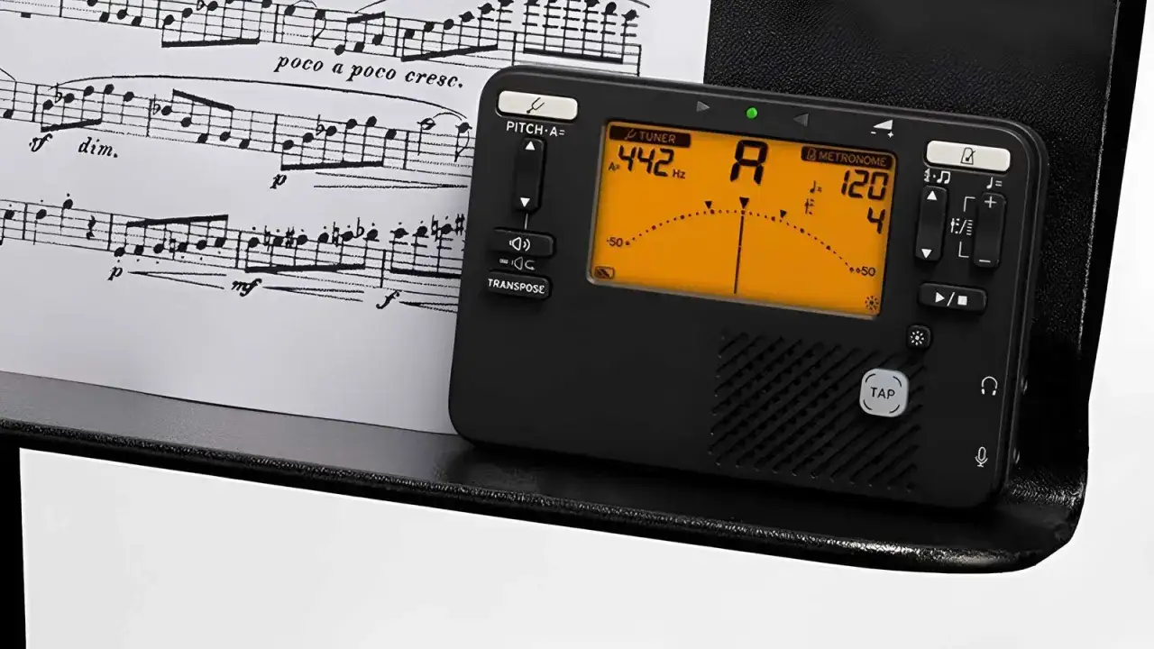 Elektroniczny metronom i tuner obok nut. Pomaga w nauce, jak liczyć takty w muzyce, utrzymując stałe tempo.