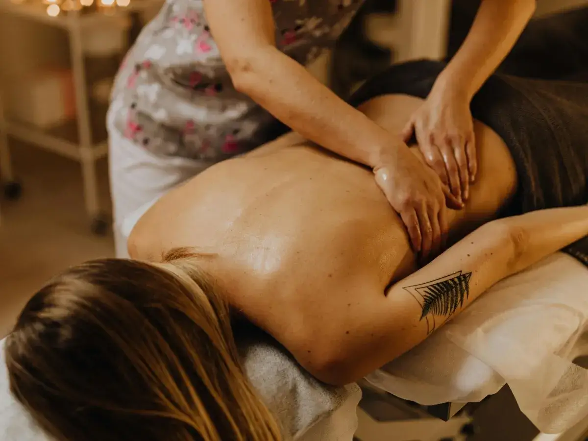 Masaż balijski: czy na masażu balijskim trzeba się rozebrać? Terapeuta masuje plecy klienta.