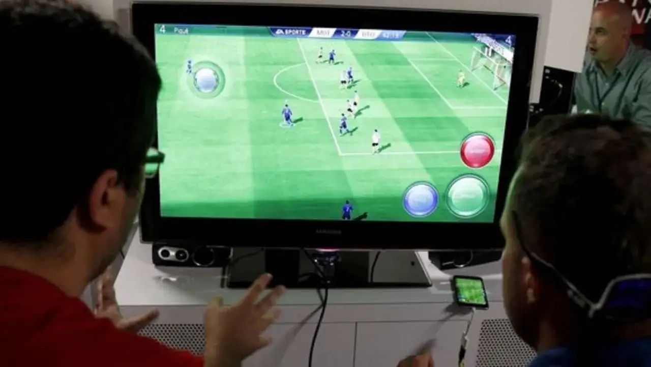 Dwóch mężczyzn gra w piłkę nożną na telewizorze, korzystając z gry na telewizor bez konsoli.