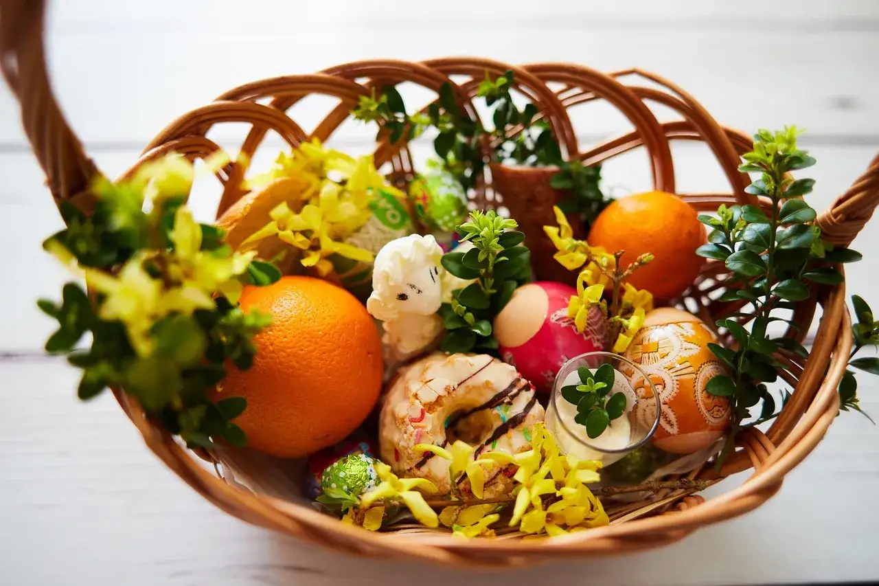 Inspiracja, jak udekorować koszyczek wielkanocny: pisanki, pomarańcze, babeczka i zieleń tworzą wiosenną kompozycję.
