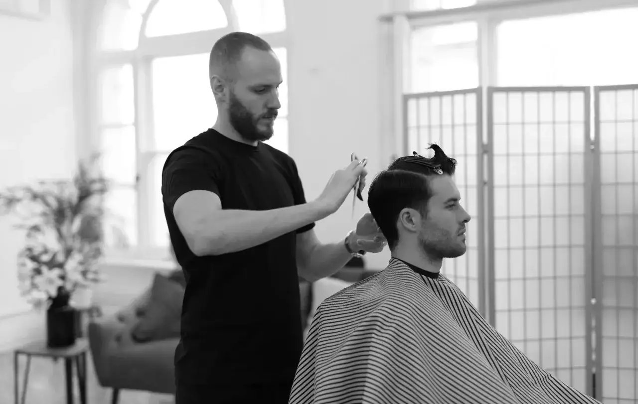 Mistrz fryzjerstwa wykonuje strzyżenie męskie dla początkujących, precyzyjnie modelując włosy klienta.