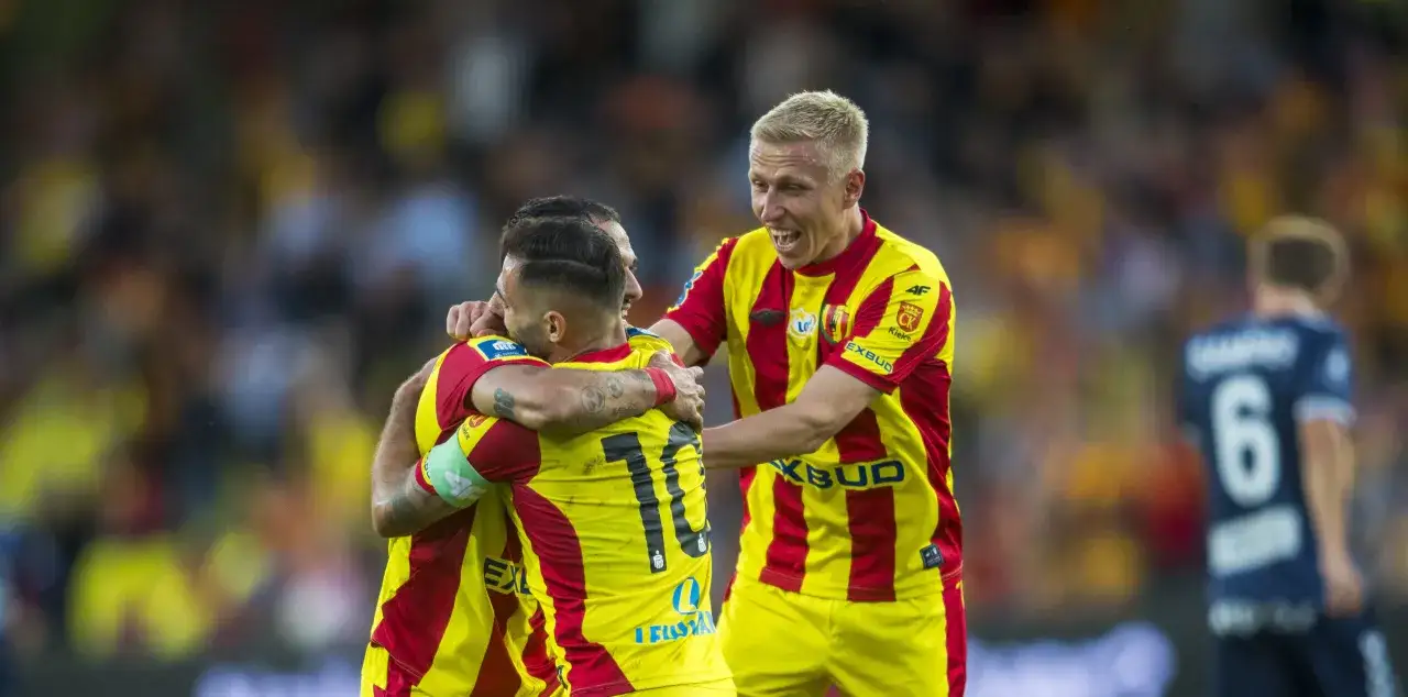 Radość zawodników Korony Kielce po zdobytej bramce. Piłkarze w żółto-czerwonych strojach świętują razem na boisku.