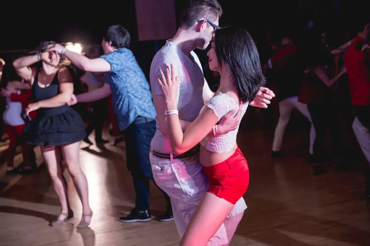 Para dowiedzieć się, bachata co to, zobacz tę parę tańczącą zmysłowo na parkiecie. W tle inni też się bawią.