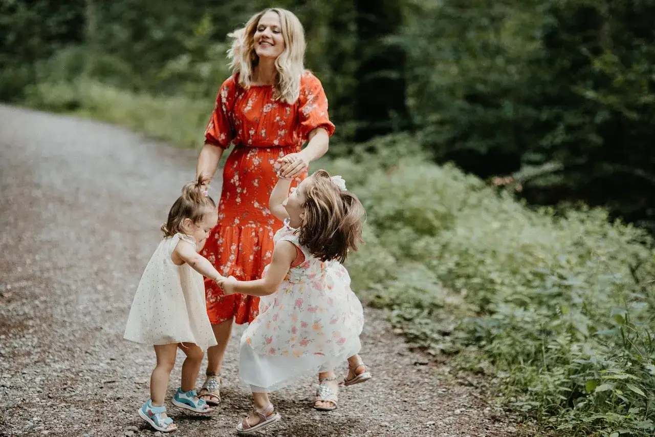 Mama z c&oacute;rkami tańczy na leśnej ścieżce. Radosne zabawy rytmiczne dla dzieci na łonie natury.