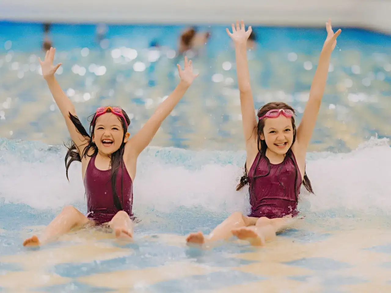 Dwie dziewczynki w goglach i strojach kąpielowych cieszą się wodą. Zastanawiasz się, ile kosztuje doba w hotelu Gołębiewski w Karpaczu?