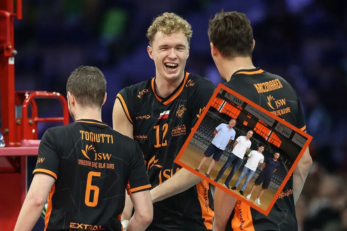 Siatkarze Jastrzębski Węgiel w szatni, jeden z nich śmieje się radośnie. W tle zdjęcie zespołu z zarządem.