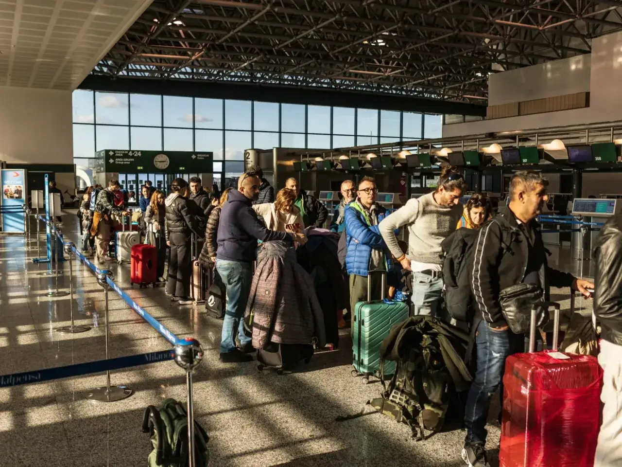 Kolejka do odprawy na lotnisku. Czy do Rzymu potrzebny jest paszport? Wszyscy podróżni z bagażami czekają na swoją kolej.