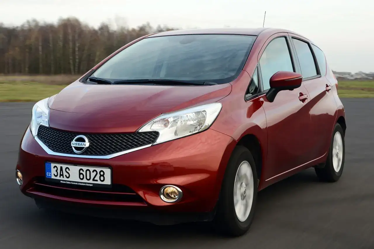 Czerwony Nissan Note jedzie po drodze.