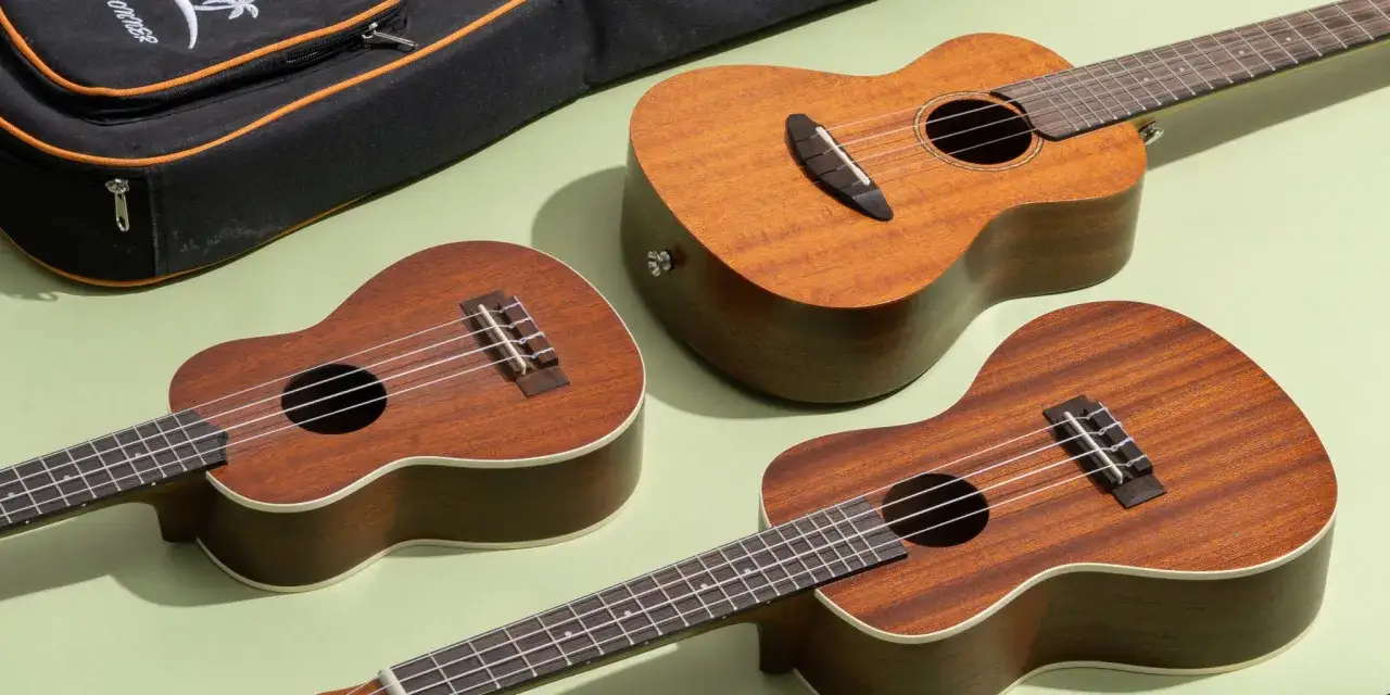 Trzy drewniane ukulele leżą obok czarnego futerału. To małe, czterostrunowe instrumenty, idealne do nauki gry.