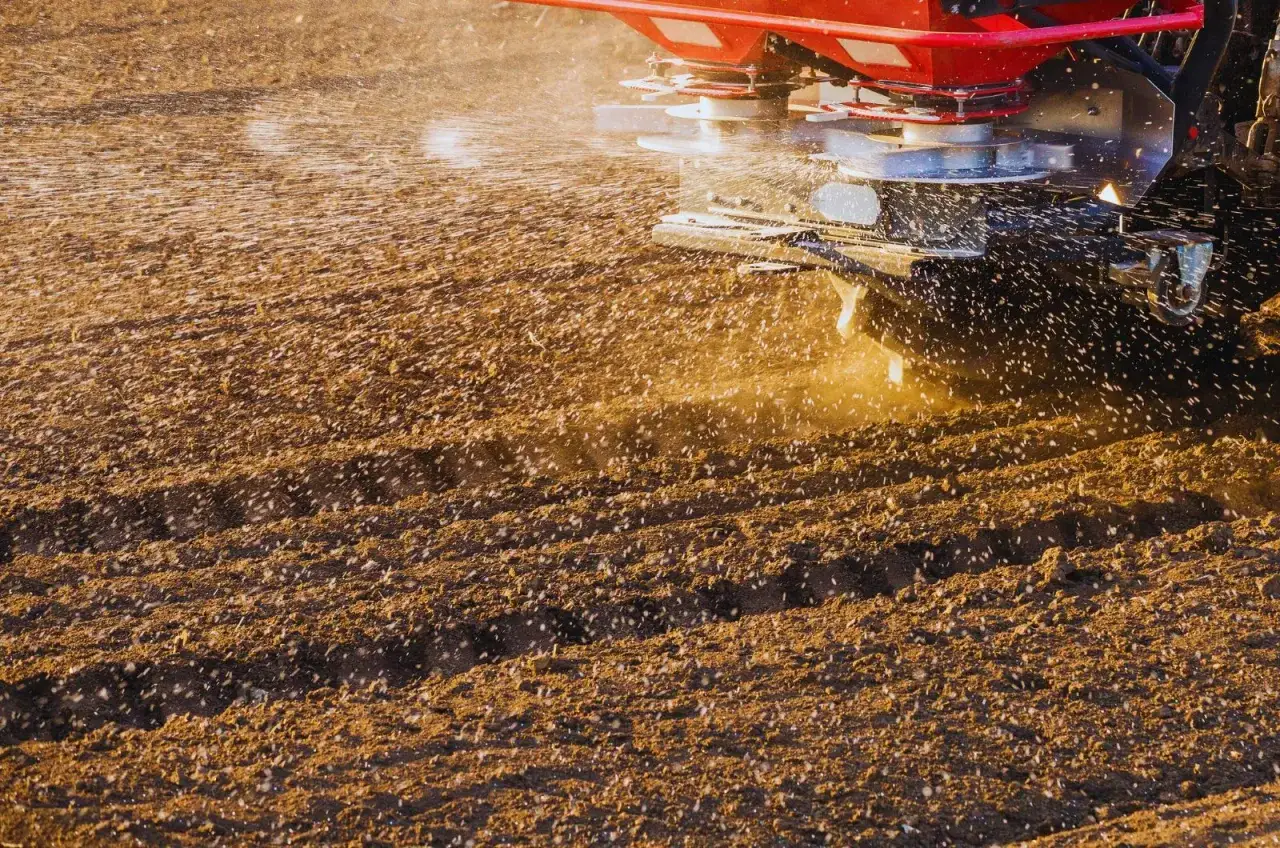 Rozsiewacz wapna na polu. Wapnowanie gleby poprawia jej strukturę i żyzność, co daje lepsze plony.