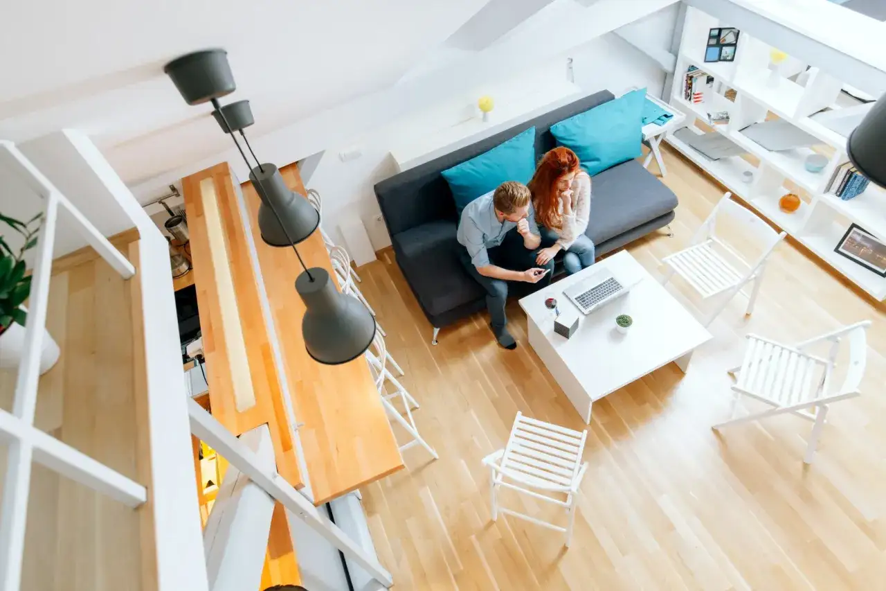 Para, omawiający jak wynajmować mieszkanie krótkoterminowo, siedzi na kanapie w nowoczesnym wnętrzu.