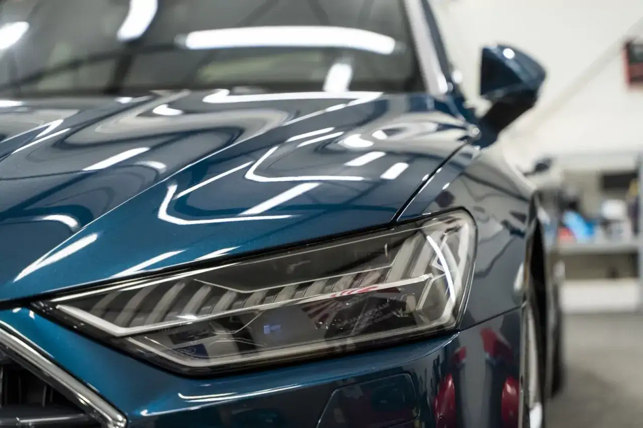 Błyszcząca maska samochodu w kolorze granatowym. Zastanawiasz się, ile kosztuje pomalowanie maski w samochodzie?