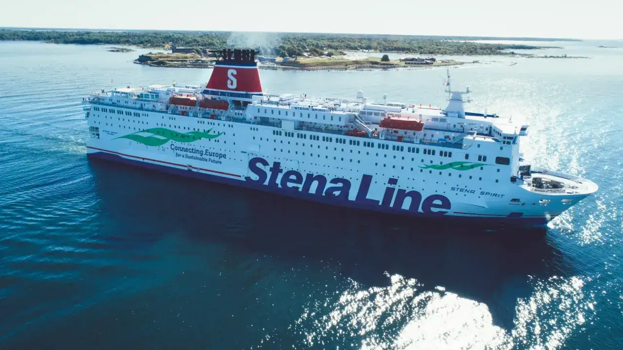 Prom na wodzie z napisem Stena Line. Statek płynie po błękitnym morzu, w tle zielone wyspy.