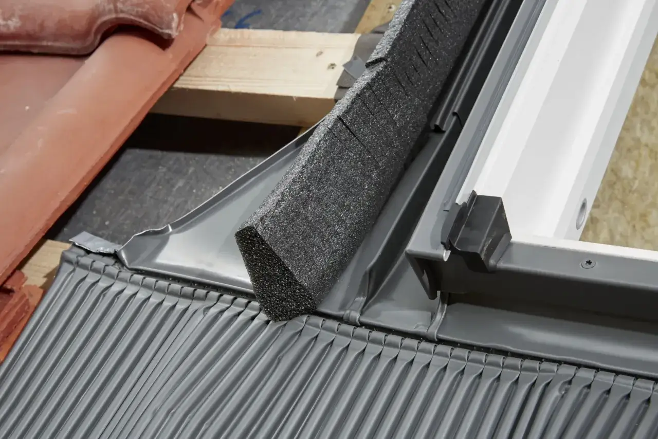 Detale montażu okna dachowego: izolacja, blacha i dach&oacute;wka. Wymiana okna dachowego w trakcie prac.