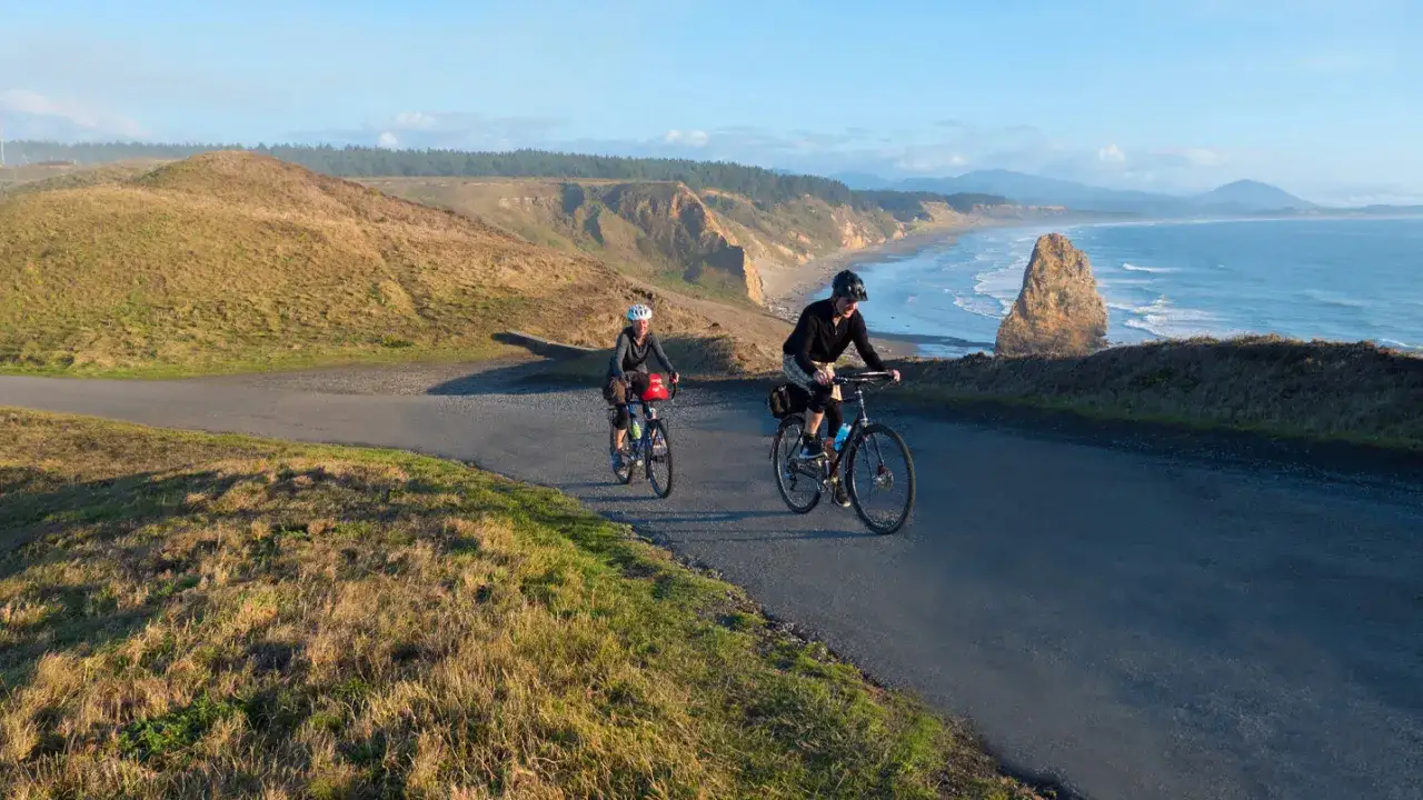 Dwie osoby na rowerach przemierzają malowniczą trasę wzdłuż wybrzeża. Co daje jazda na rowerze? Wolność, piękne widoki i aktywność na świeżym powietrzu.