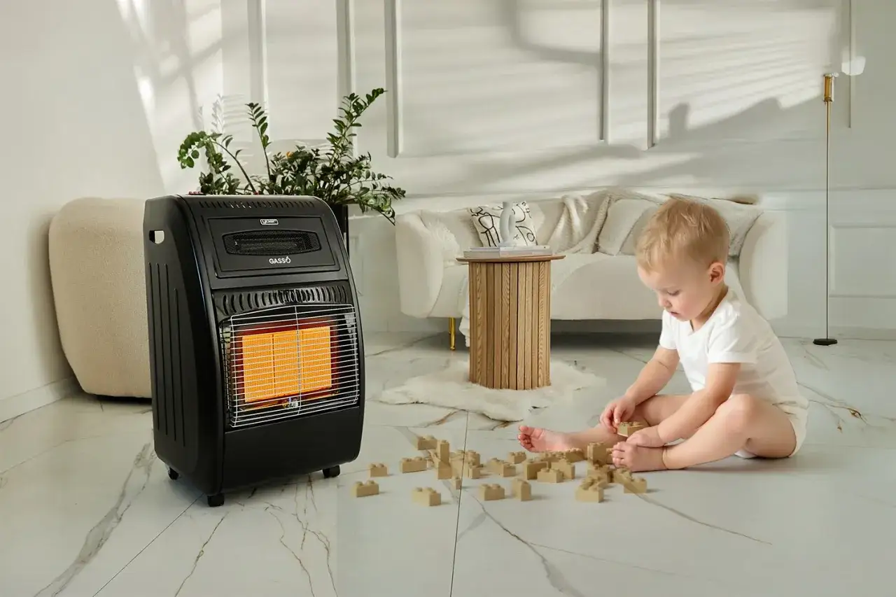 Małe dziecko bawi się klockami przy piecyku gazowym, kt&oacute;ry zapewnia ciepło w pokoju.