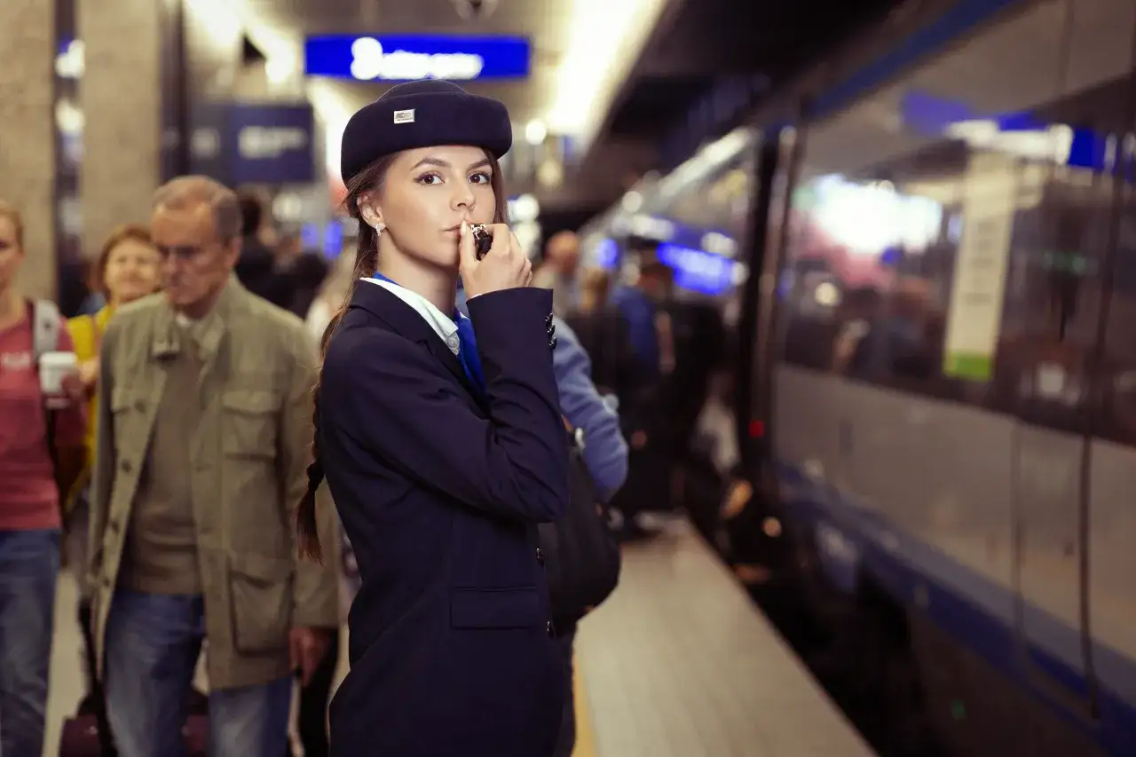Młoda konduktorka Intercity na peronie, z gwizdkiem w dłoni. Marzysz, jak zostać konduktorem Intercity?