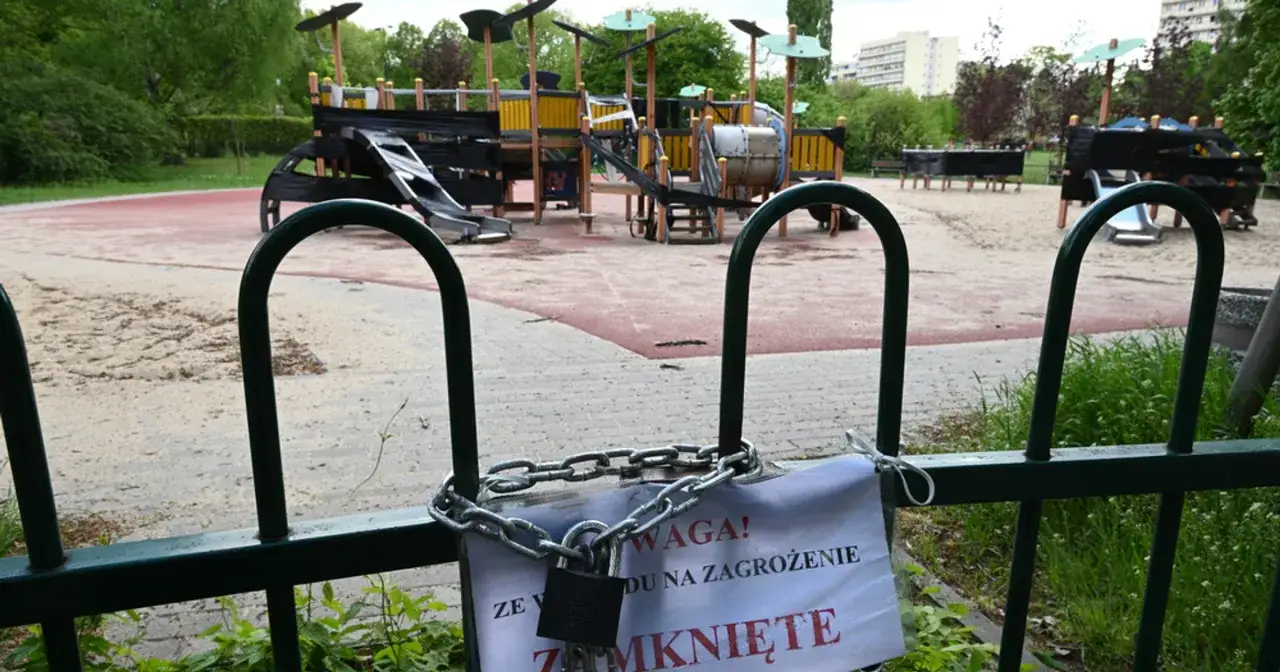 Zamknięte place zabaw do odwołania. Kłódka i łańcuch na ogrodzeniu, tabliczka informuje o zagrożeniu.