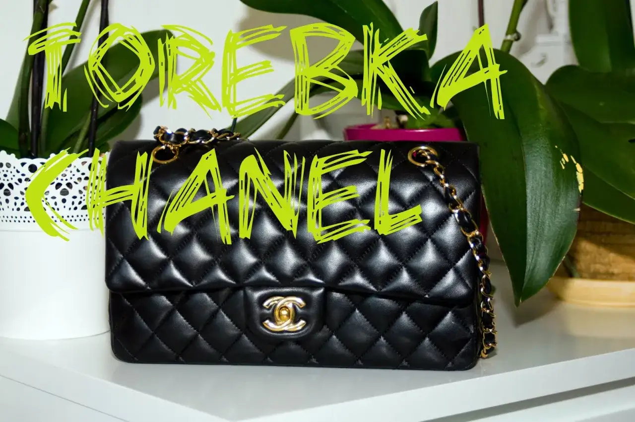 Elegancka, pikowana torebka Chanel w kolorze czarnym, z charakterystycznym złotym łańcuszkiem i logo. Obok stoją rośliny.