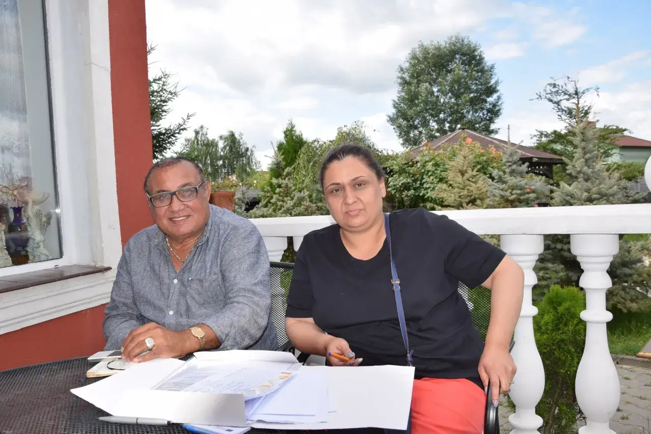 Agnieszka, córka Don Vasyla, siedzi przy stole z dokumentami. Obok niej mężczyzna w okularach.