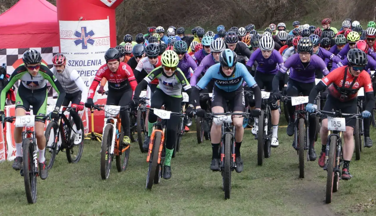 Start maratonu rowerowego. Kolarze w kaskach i strojach sportowych ruszają do walki na trasie.