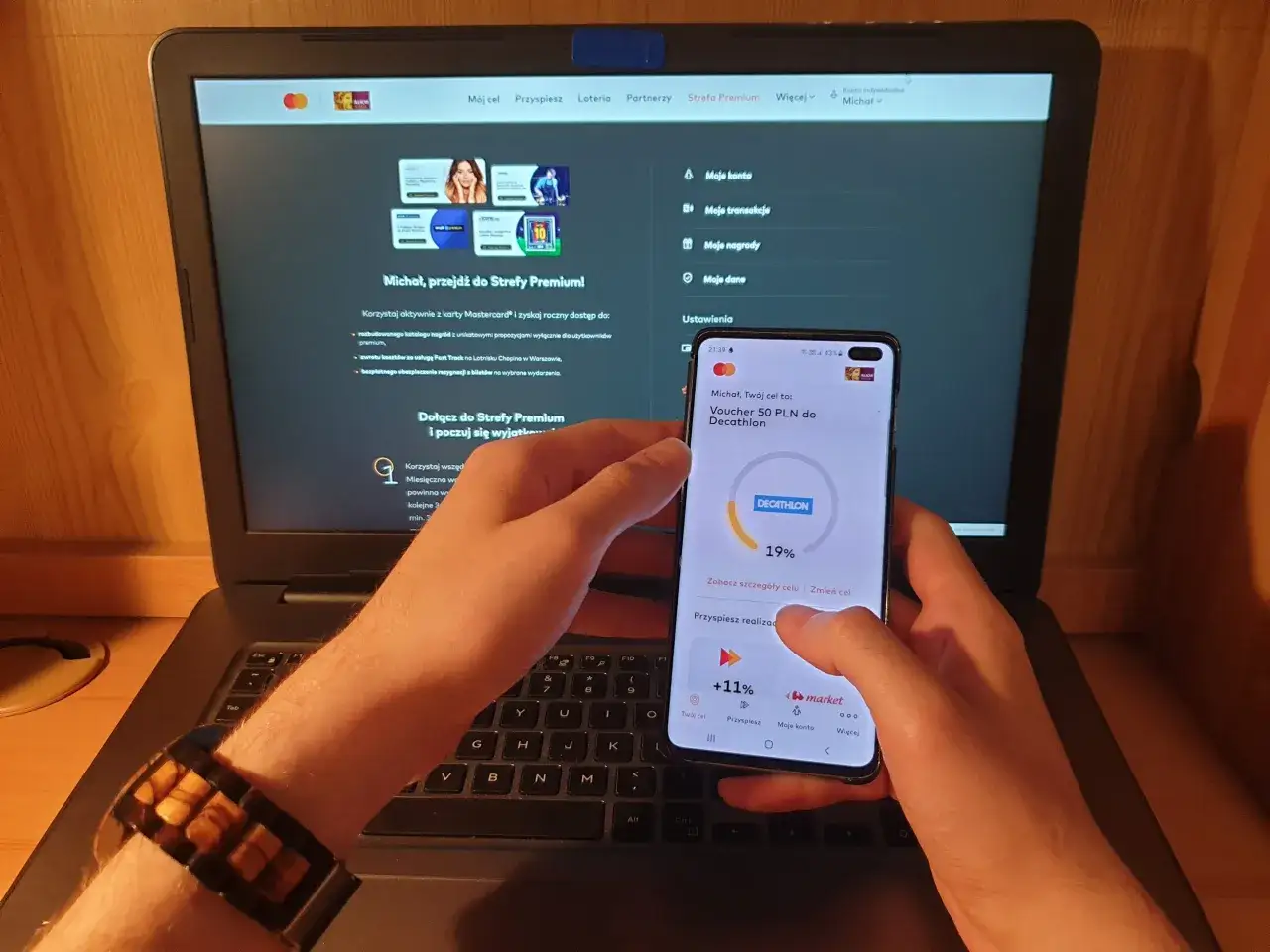 Michał korzysta z programu lojalnościowego, sprawdzając na telefonie voucher do Decathlonu.