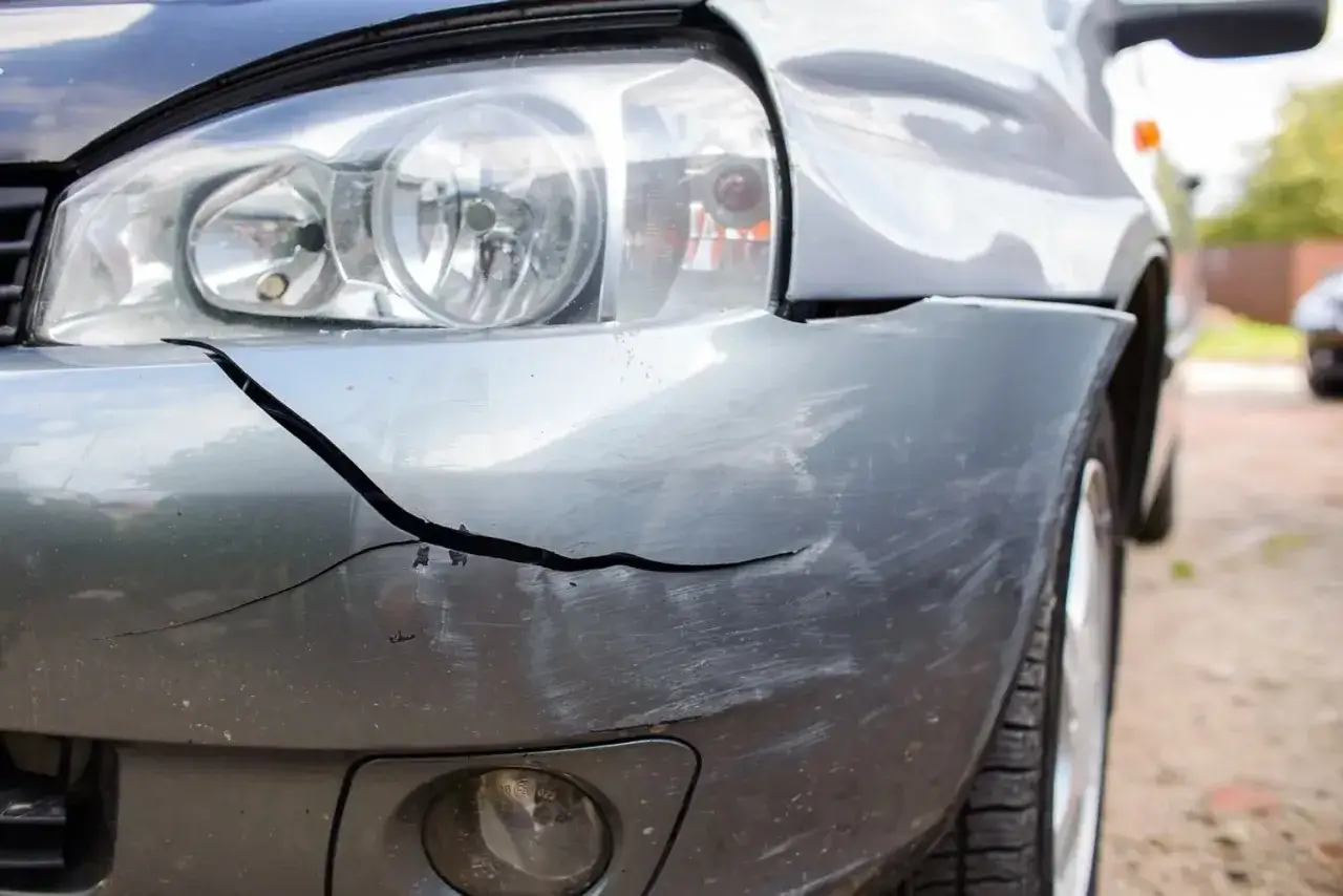 Pęknięty plastikowy zderzak samochodu, pokazujący uszkodzenie i rysy. Dowiedz się, jak naprawić pęknięty zderzak plastikowy domowym sposobem.