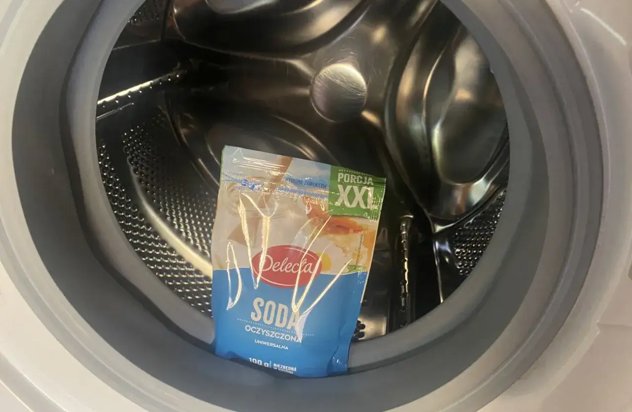 Wnętrze pralki z saszetką sody oczyszczonej. Poznaj prawdziwe powody dla których pralka brudzi ubrania ciemnymi plamami po praniu.