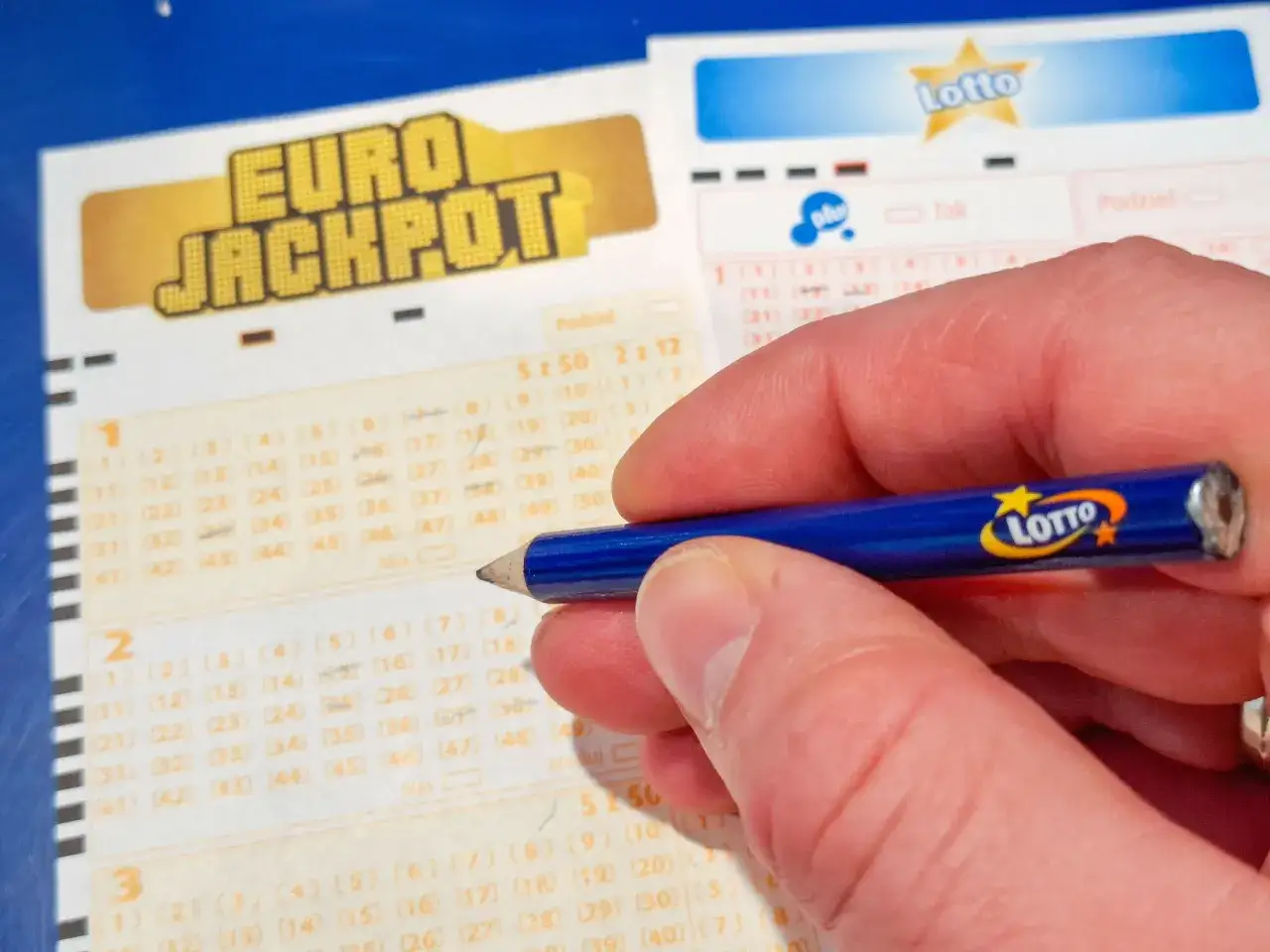 Dłoń z ołówkiem Lotto zaznacza liczby na kuponie Eurojackpot. Losowania Eurojackpot odbywają się dwa razy w tygodniu.