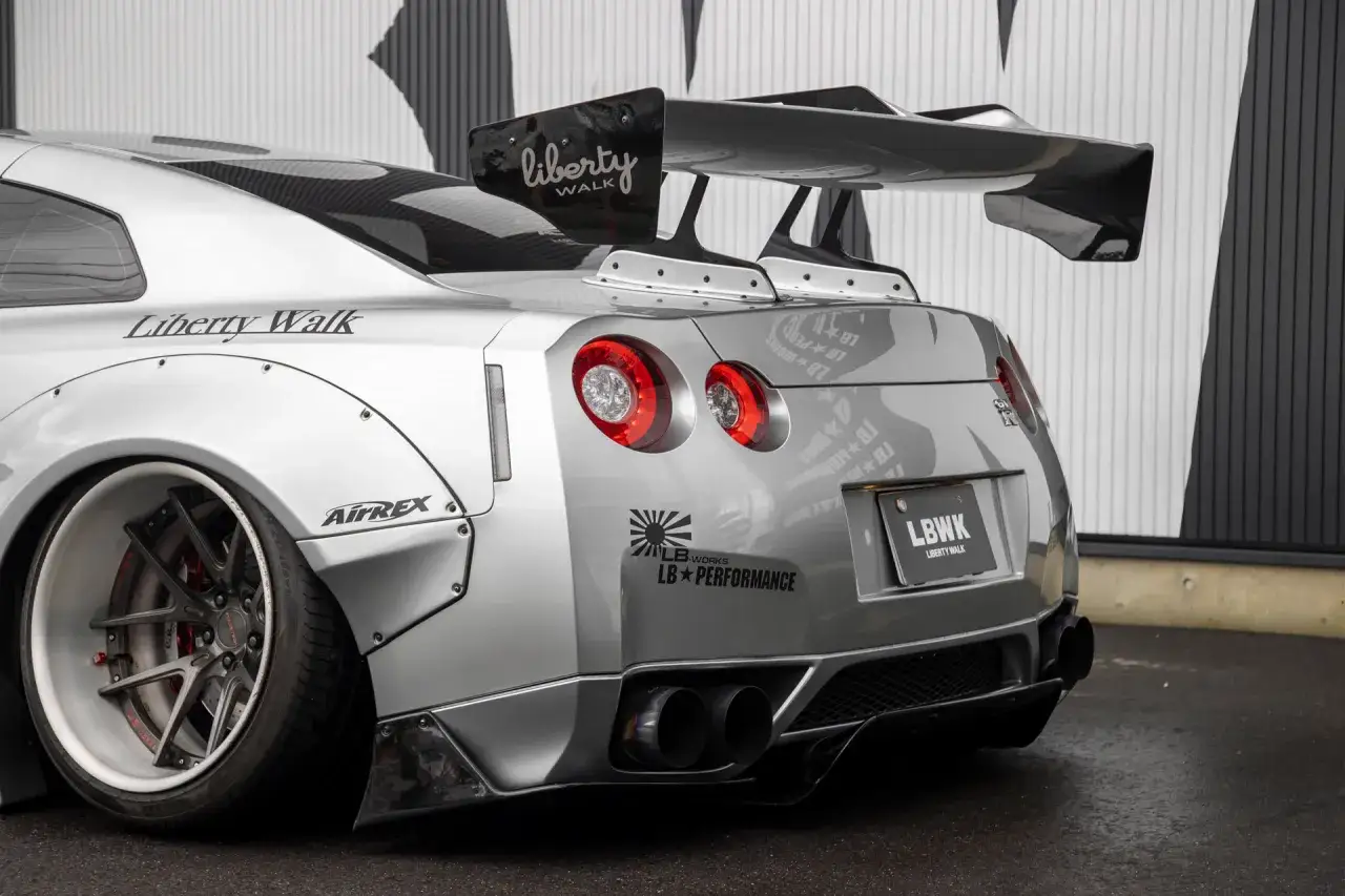 Srebrny Nissan GTR R35 z szerokim body kitem Liberty Walk i masywnym skrzydłem.