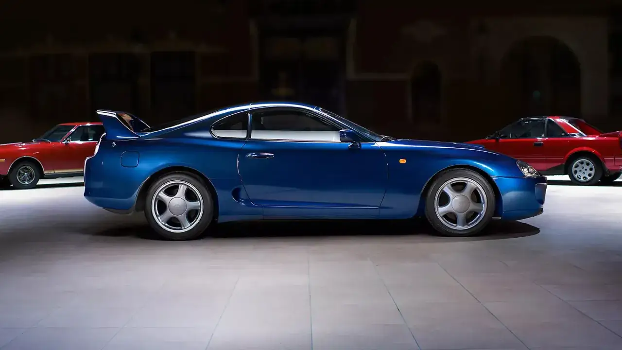 Niebieska Toyota Supra obok czerwonych klasyk&oacute;w. Zastanawiasz się, ile kosztuje Toyota Supra?