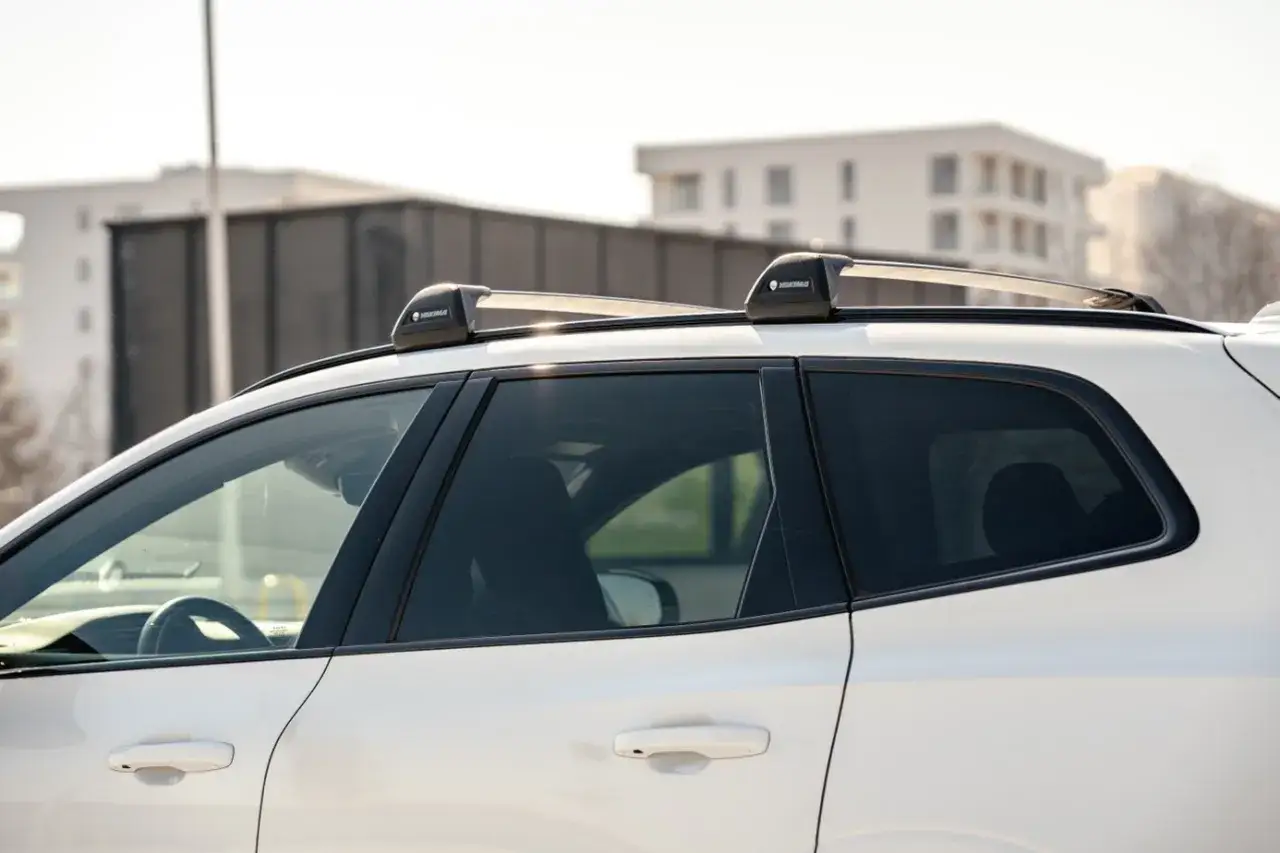 Montaż relingów dachowych na białym samochodzie. Gotowy na podróż z bagażem na dachu.