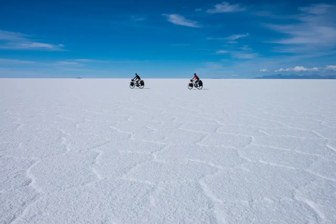 Dwóch rowerzystów przemierza Salar de Uyuni, białą pustynię solną, z czego słynie Boliwia.