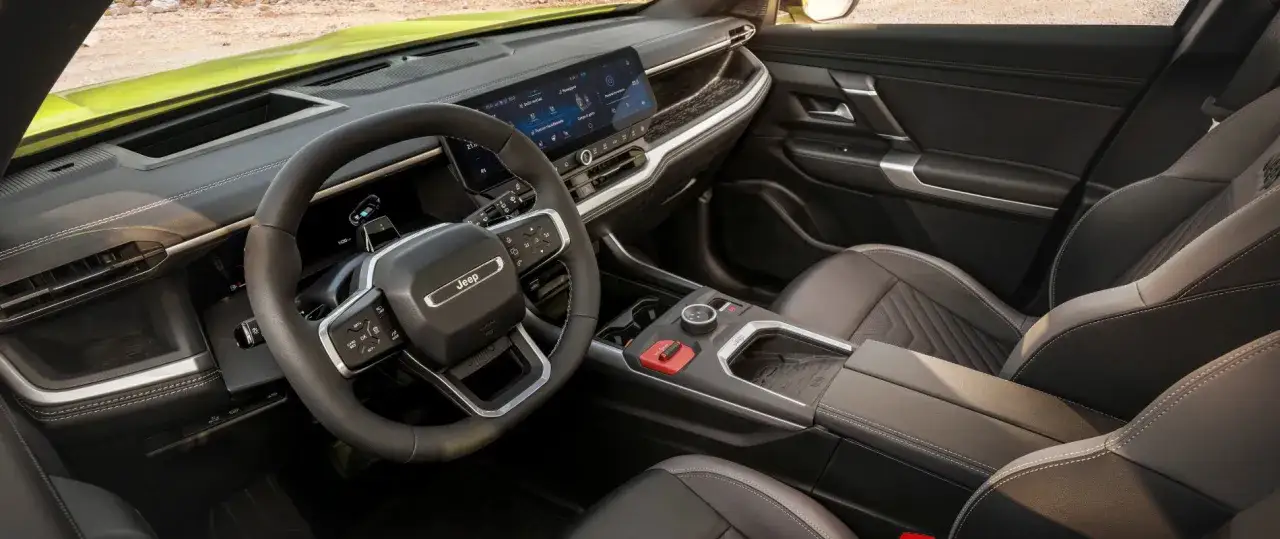 Wnętrze nowego Jeep Compass z ekranem dotykowym, kierownicą i fotelami.