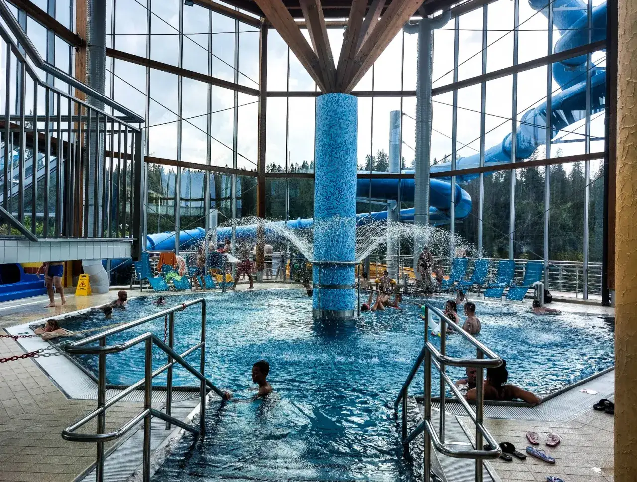 Wesoła zabawa w aqua parku Bukowina. Dzieci i dorośli kąpią się w basenie, a w tle widać zjeżdżalnie i wodne atrakcje.