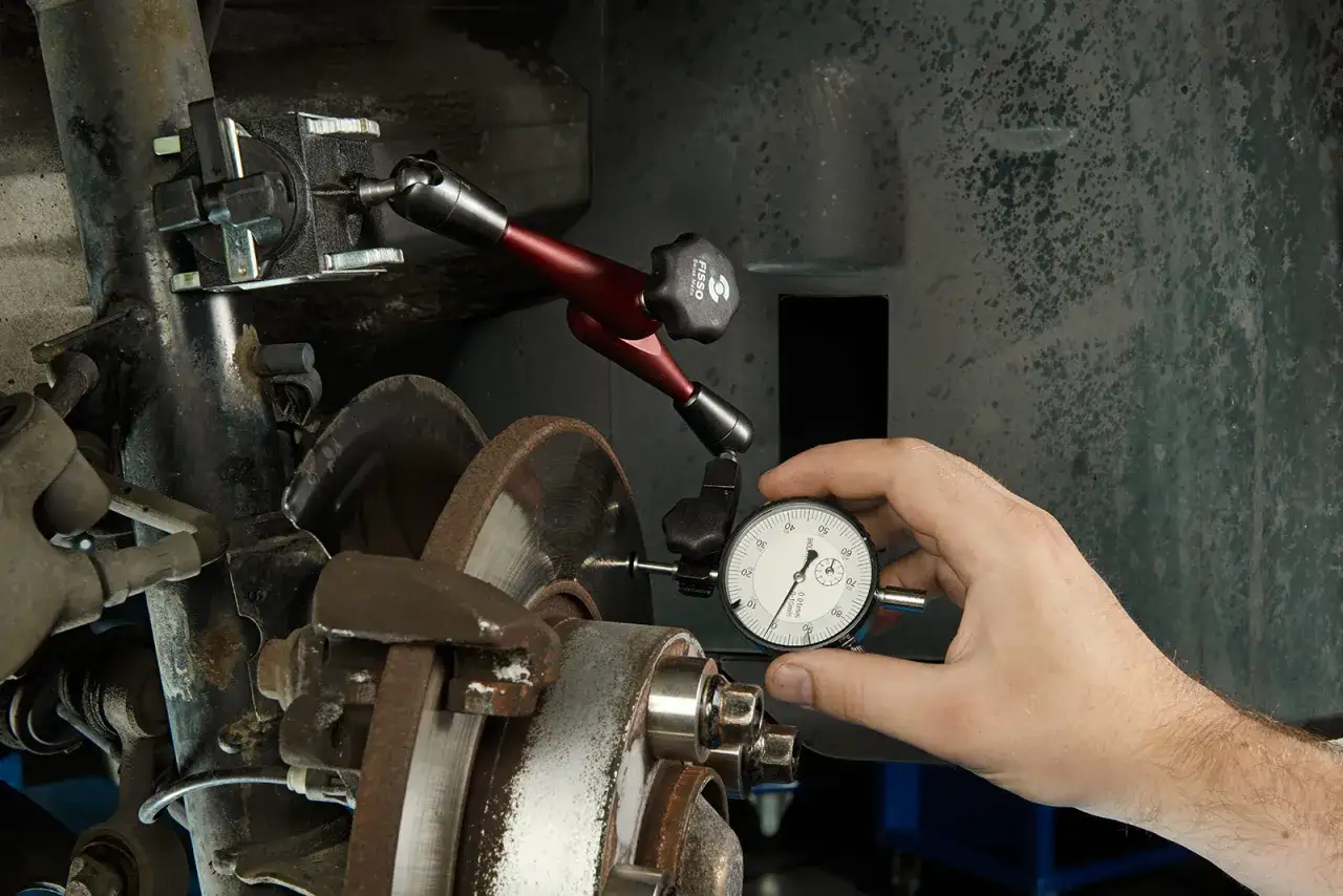 Mechanik sprawdza bicie na kierownicy za pomocą czujnika zegarowego.