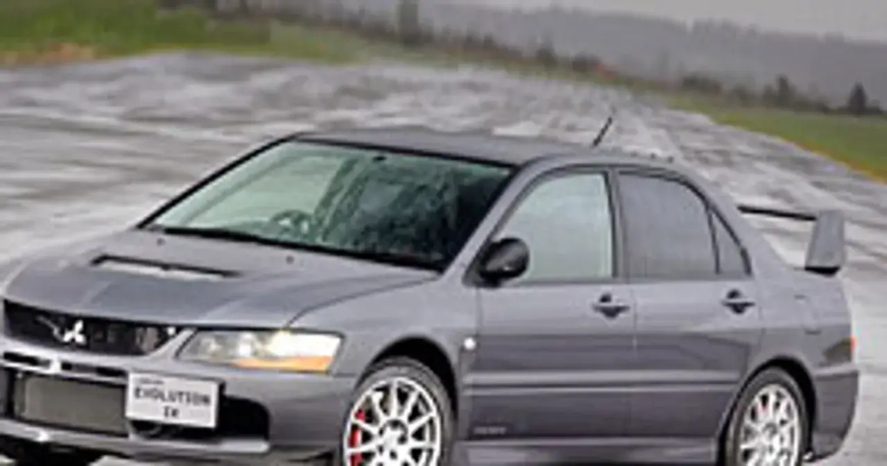 Szary Mitsubishi Lancer Evolution IX na mokrej nawierzchni.