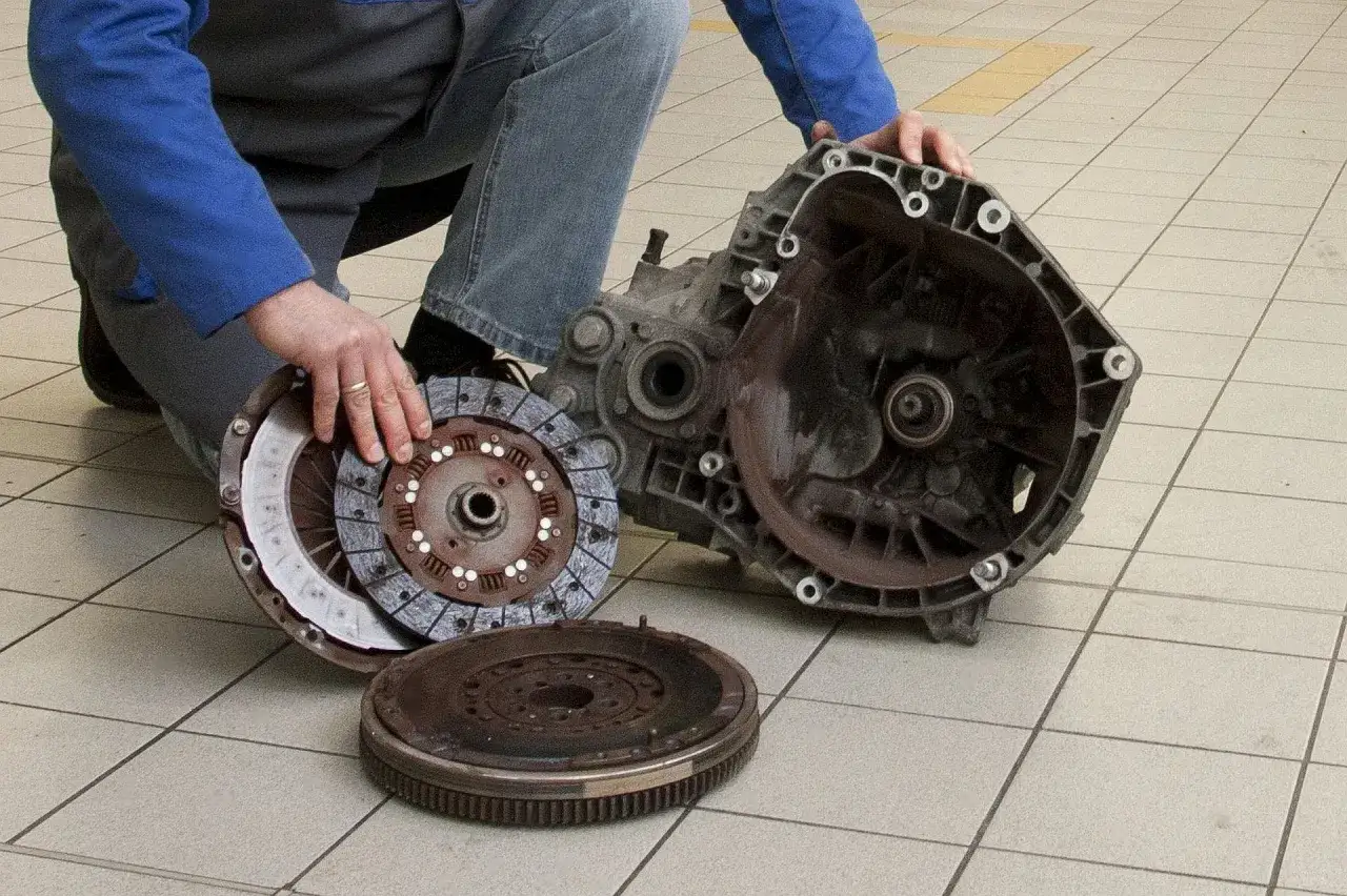 Mechanik pokazuje elementy sprzęgła: tarczę, docisk i koło zamachowe. Objawy zużycia łożyska oporowego mogą być r&oacute;żne.