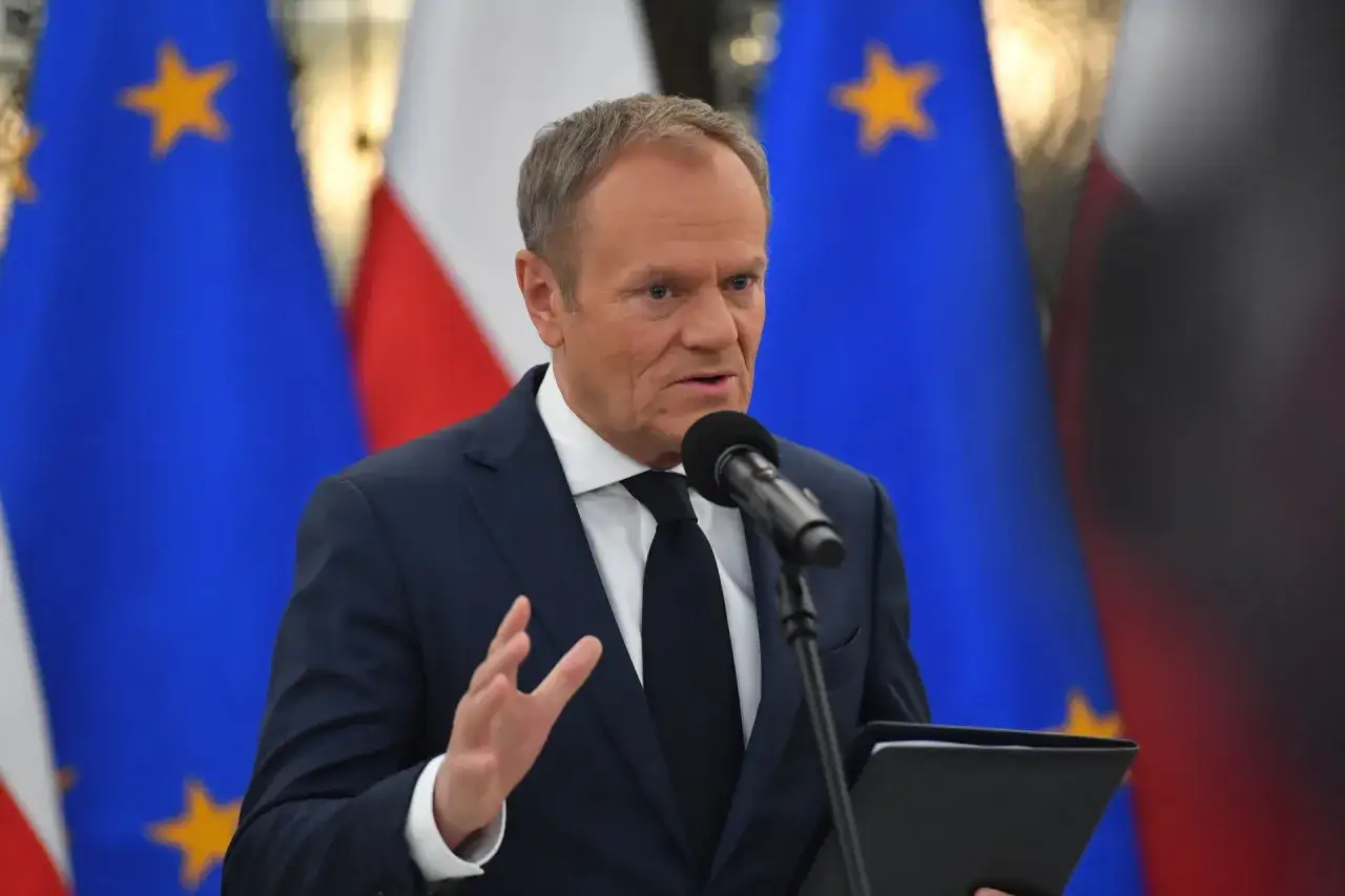 Donald Tusk przemawia na tle flag Polski i UE. Czy jego emerytura na rękę jest wysoka?