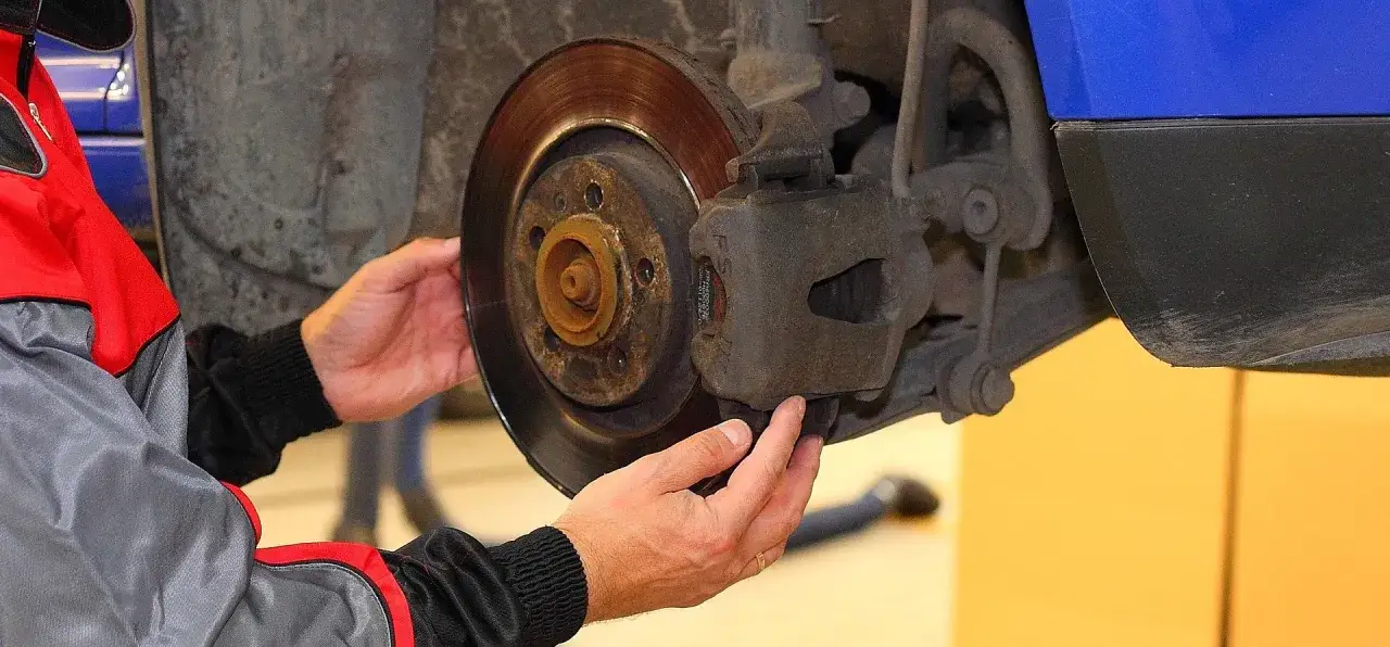 Mechanik sprawdza klocki hamulcowe, dotykając zacisku hamulcowego.