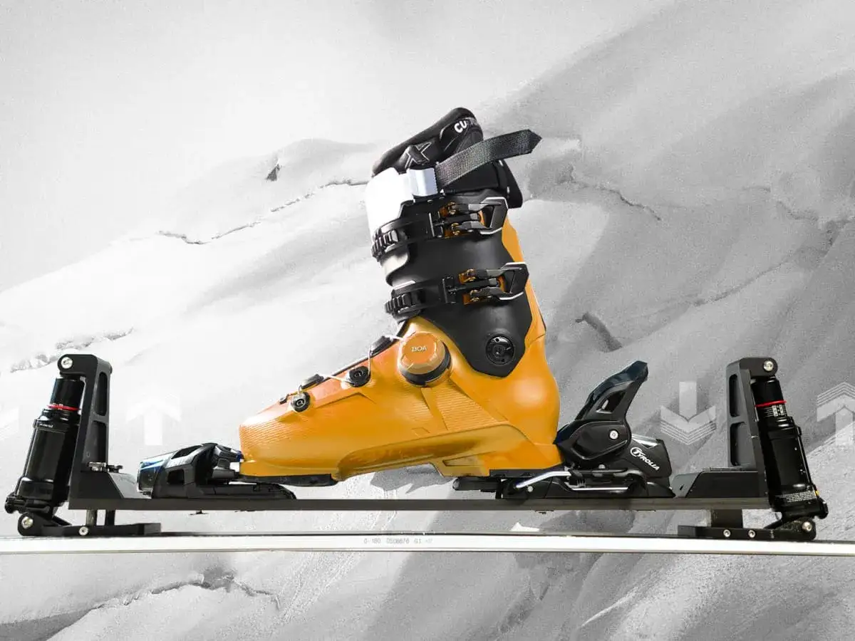 Pomarańczowy but narciarski na stelażu. Czy buty narciarskie pasują do snowboardu? Nie, to sprzęt do jazdy na nartach.