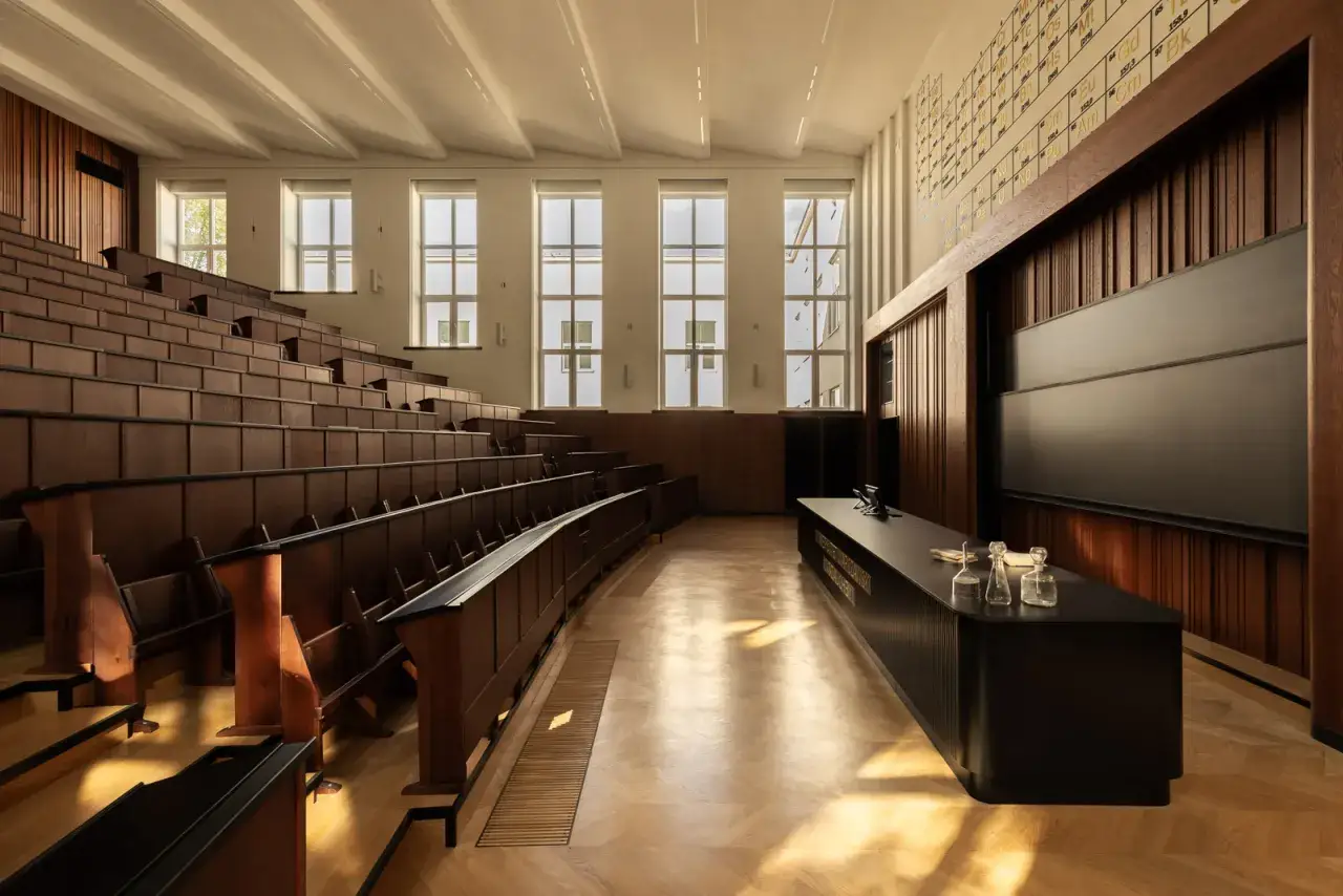 Klasyczna aula uniwersytecka z drewnianymi ławami i tablicą. Idealne miejsce do nauki, co to aula?