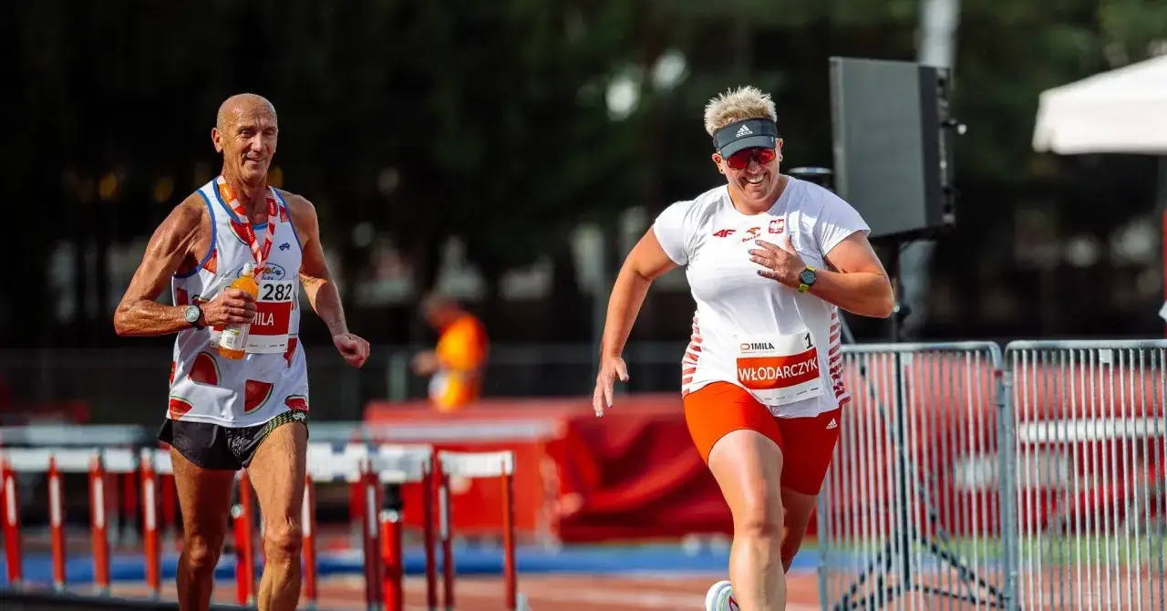 Uśmiechnięta kobieta i mężczyzna biegną w zawodach na 1000m. Kobieta ma numer 1, mężczyzna 282.