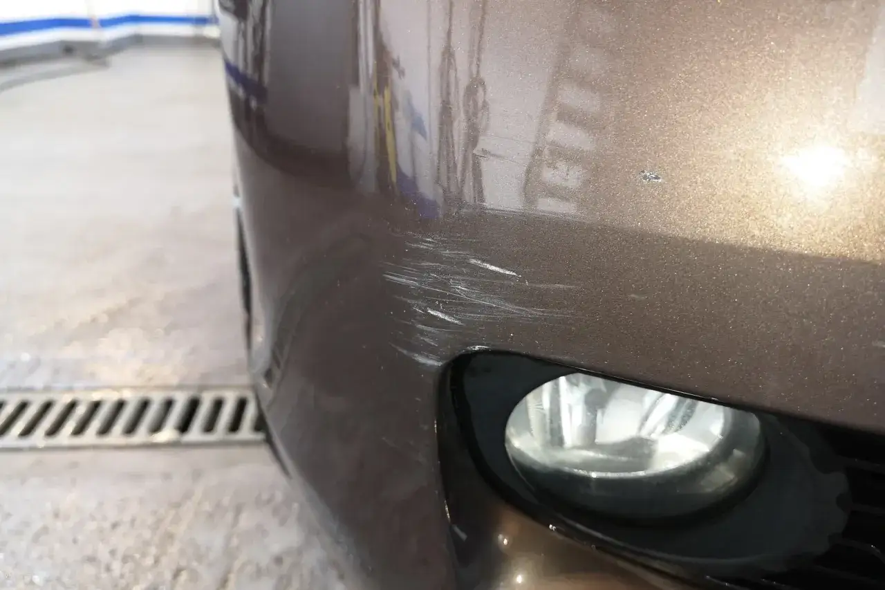 Widoczne głębokie rysy na brązowym zderzaku samochodu. Dowiedz się, jak usunąć rysy z samochodu i przywrócić mu dawny blask.